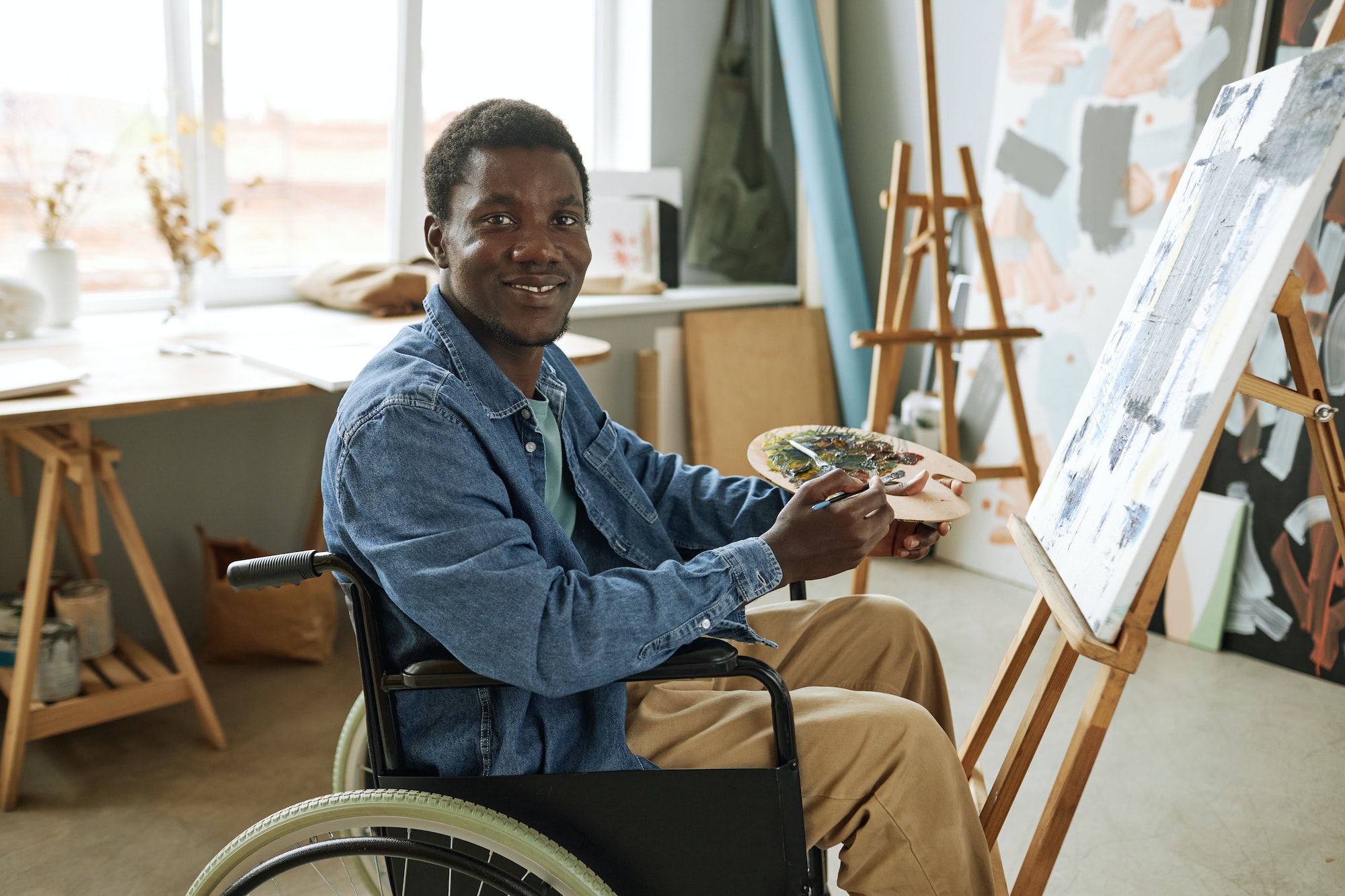 Young successful painter with disability sitting in wheelchair